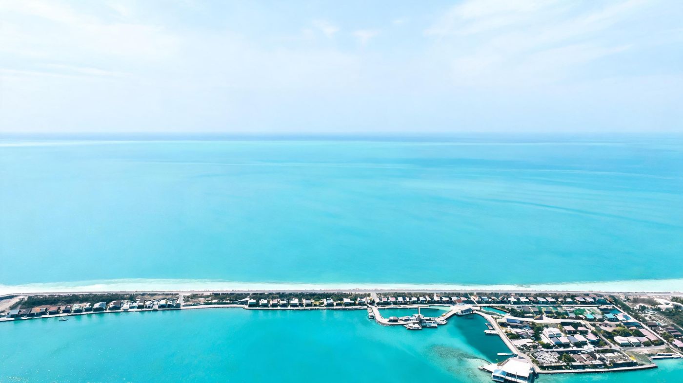 Aerial view of reclaimed land and a harbour meeting a turquoise lagoon